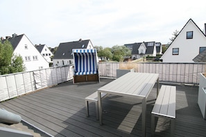 Eine Dachterrasse mit Liegestuhl, Tisch und Bank.