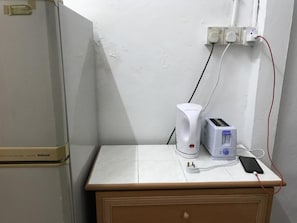 Eine Küchenzeile mit einem weißen Kühlschrank, einem Toaster und einer Kaffeemaschine auf einer gefliesten Arbeitsfläche.