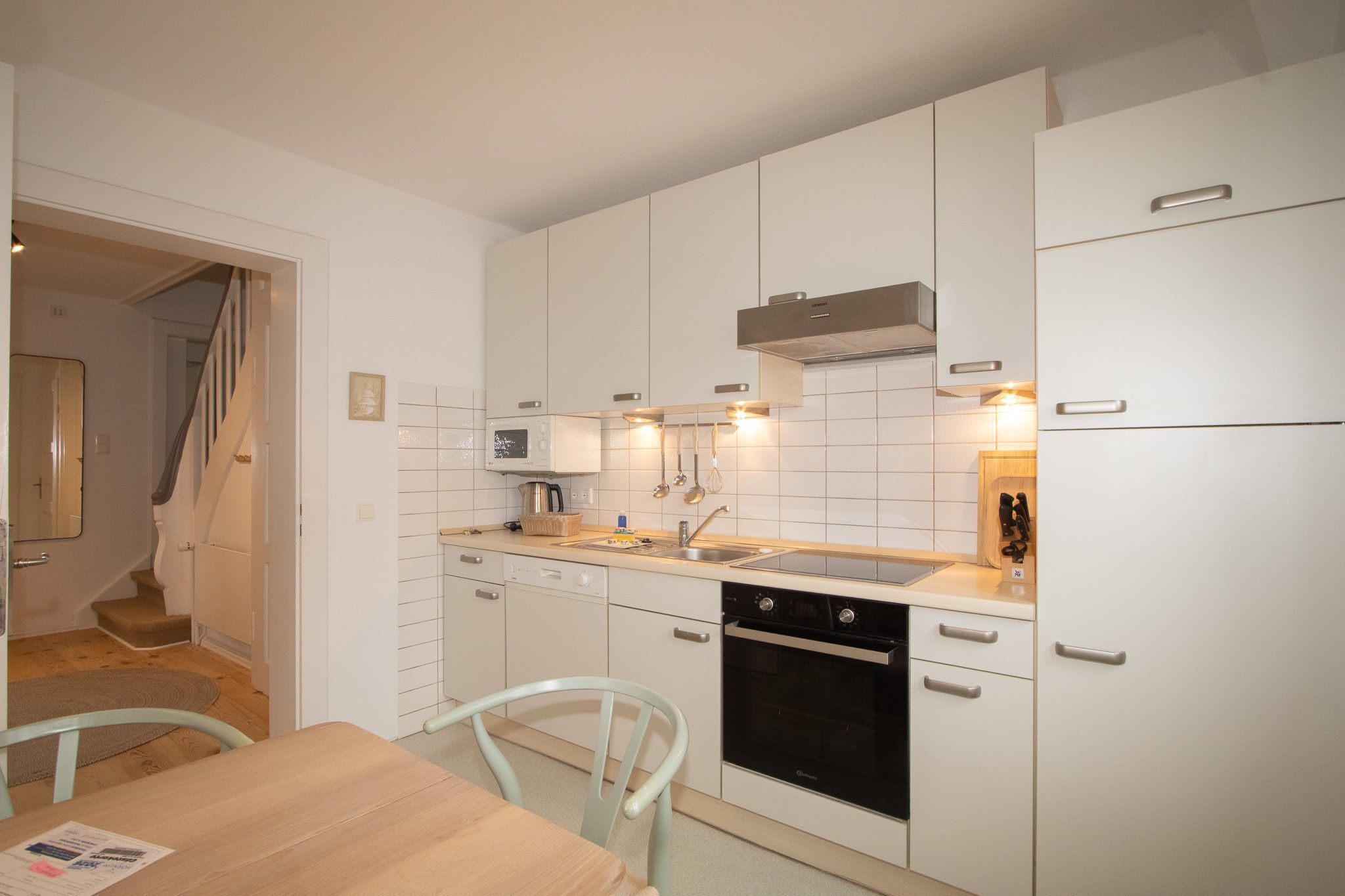 Une cuisine de taille réduite avec des meubles blancs, un four à micro-ondes, un évier et un lave-vaisselle.