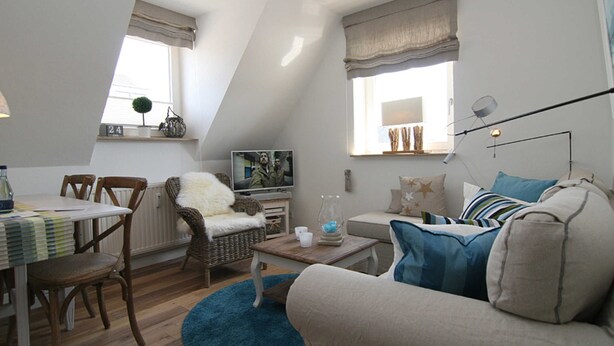 Ein gemütliches Wohnzimmer mit Esstisch, einer Couch und einem Fernseher.