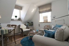 Ein gemütliches Wohnzimmer mit Esstisch, einer Couch und einem Fernseher.