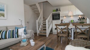 Ein modernes Wohnzimmer mit einem Couchtisch aus Holz, einer Couch mit gestreiften Kissen und einer Treppe, die in einen Küchenbereich führt.
