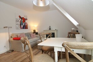 Une pièce confortable de style loft, avec une table à manger, des chaises en bois, un canapé agrémenté de coussins à motifs et un tableau accroché au mur.