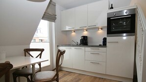 Une cuisine avec des meubles blancs, une machine à café et un four encastré.
