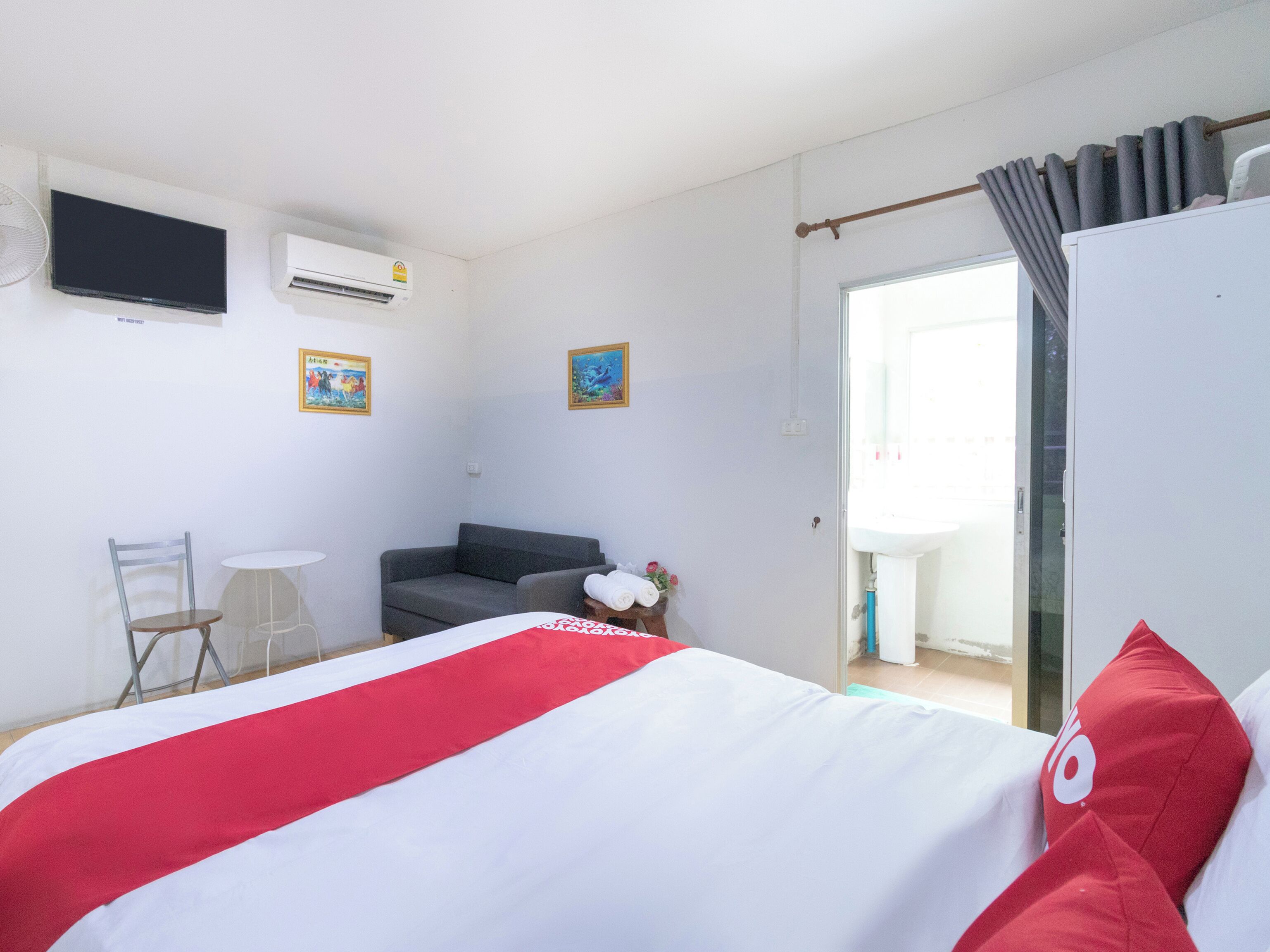 Ein Hotelzimmer mit Bett, Schreibtisch, Stuhl, Sofa, Fernseher und einem fensterbepflanzten Fenster.