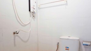 Un baño pequeño con paredes blancas, un inodoro, una ducha y un secador de manos.