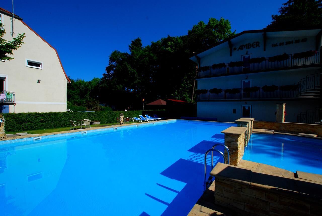 A swimming pool with lounge chairs and a building with a sign reading "AMBER".
