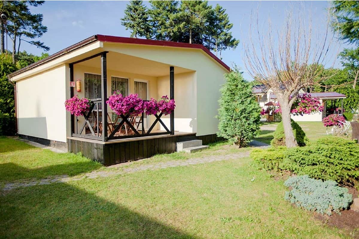A small, single-story building with a covered porch and a small garden area.