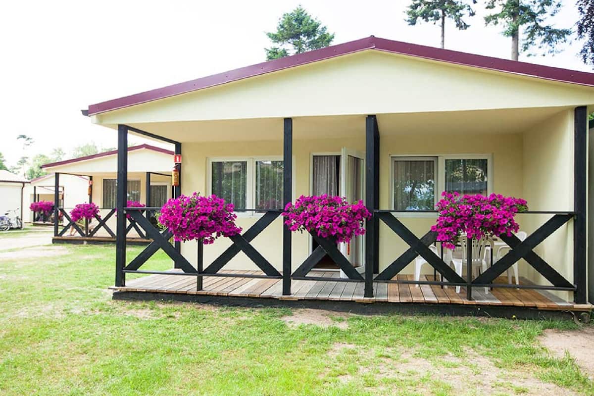 A single-story motel with a covered porch, multiple windows, and potted plants.