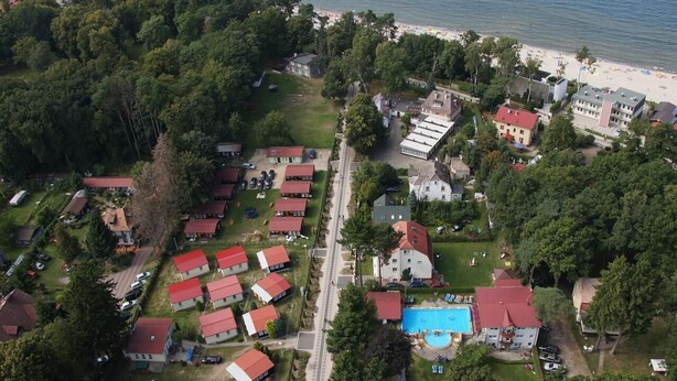 Vista aerea di una zona residenziale con case, piscina e spiaggia.