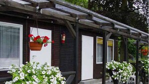 Una fila di cabine con vasi di fiori bianchi davanti e cesti di fiori appesi al portico.