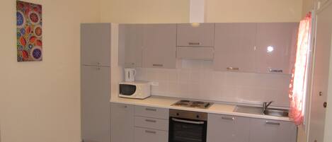 A compact kitchen with a microwave, oven, and sink.