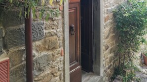 Ein Steinhaus mit einer Holztür und einem kleinen Vordach über dem Eingang.