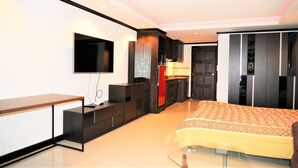 A modern bedroom with a bed, a TV mounted on the wall, a kitchen area, and a wardrobe. - High Floor Apartment at Angket (Pattaya)