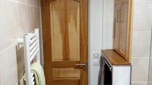 A bathroom with a wooden door, a towel rack with a towel, a radiator, and a cabinet above the sink. - Apartment La Musette Historic Center of Dijon (Dijon)