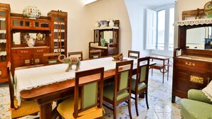 A dining area with a wooden table, chairs, and a small elephant figurine. There is a mirror and a cabinet with glass doors.