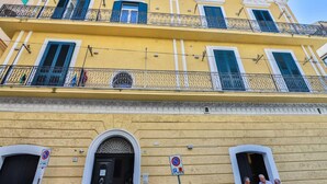 A yellow building with balconies, a black door, and a no parking sign.