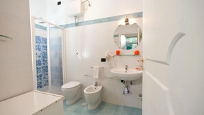 A bathroom with a toilet, bidet, sink, and a shower area.