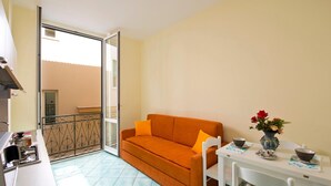 Un espace de vie compact comprenant un canapé, une table à manger et un balcon doté d’une balustrade.