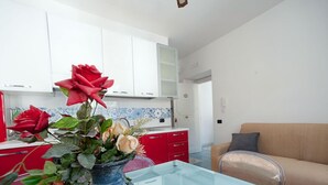 Eine moderne Küche mit weißen Schränken, einer roten Arbeitsplatte und einer Glasplatte mit Blumen in einer Vase.