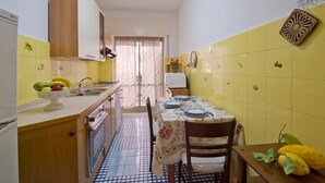 Una cocina compacta con baldosas amarillas, una mesa de comedor con platos y un frutero en la encimera.