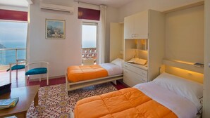 Habitación de hotel con dos camas, un escritorio, una silla, un balcón con vistas y un cuadro en la pared.
