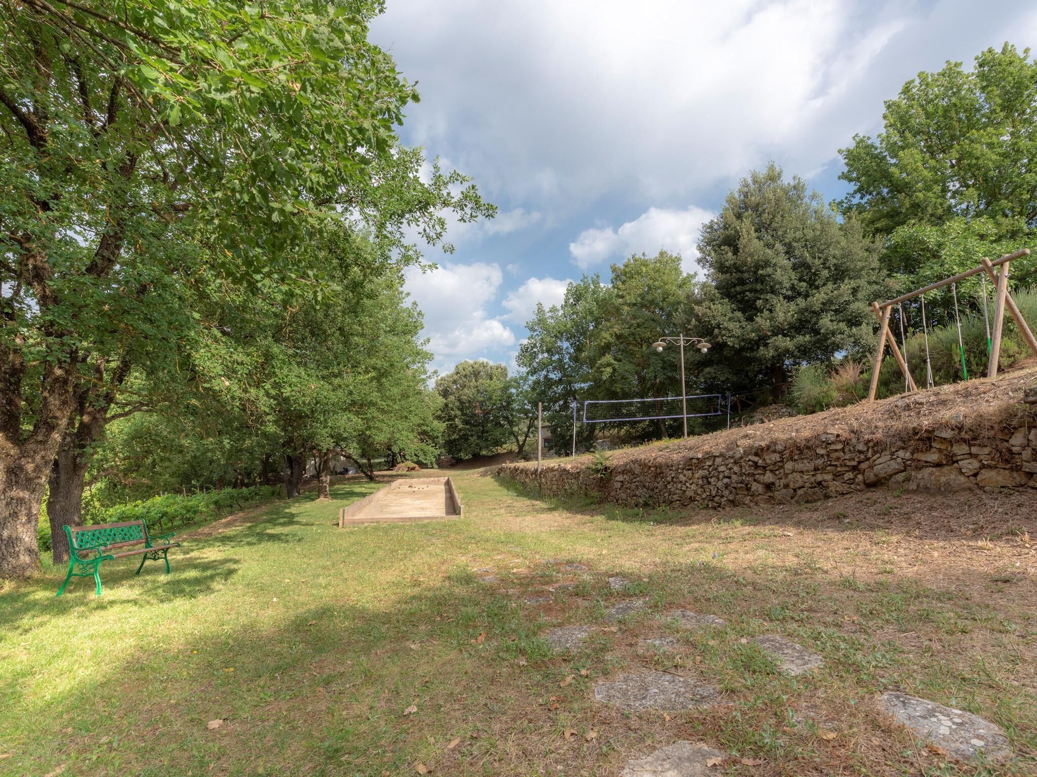 A park with a stone wall, a wooden bench, and a metal fence.