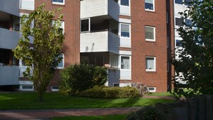 Un edificio de apartamentos de varios pisos con balcones, fachada de ladrillo y césped bien cuidado.