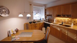 Una cocina compacta con armarios de madera, una mesa de comedor redonda e iluminación colgante.