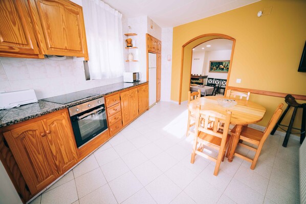 A kitchen with wooden cabinets, a built-in oven, and a dining area with a wooden table and chairs.