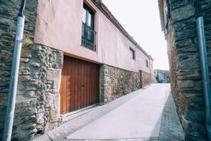 Une ruelle étroite aux murs de pierre et à la porte en bois.