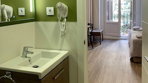 Une salle de bain moderne avec un mur vert, un lavabo blanc et un sèche-cheveux fixé au mur.