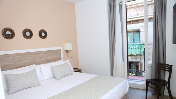 A hotel room with a bed, a nightstand, a lamp, and a view of a balcony. - Exterior studio for 3 people (Madrid)