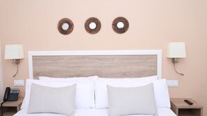 A hotel room with a wooden headboard, two bedside lamps, a telephone, and two patterned pillows. - Exterior studio for 3 people (Madrid)