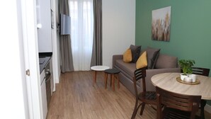 A compact living space with a kitchenette, a sofa, a dining table, and a TV. - One bedroom exterior apartment with two balconies for 4 people (Madrid)