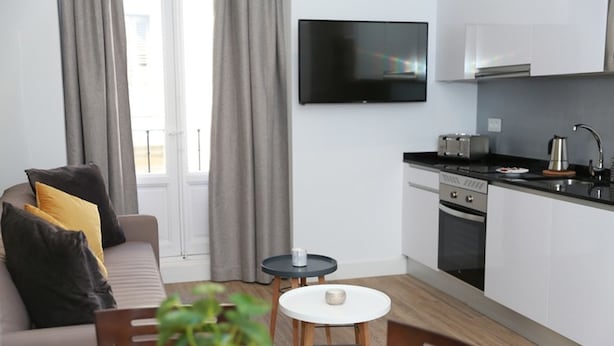 Eine moderne Wohnung mit Wohnzimmer, einer kleinen Küche und einem Essbereich.