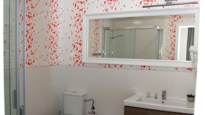 Ein Badezimmer mit Dusche, Toilette, Bidet und Waschtisch mit Spiegel.