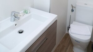 A bathroom with a white sink, a mirror, a hairdryer on the wall, and a toilet. - One bedroom penthouse with terrace for 4 people (Madrid)