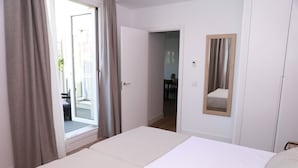 A hotel room with a bed, a door leading to a balcony, and a mirror on the wall. - One bedroom penthouse with terrace for 4 people (Madrid)