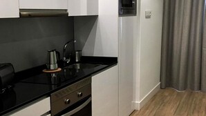 Et moderne køkken med hvide skabe, en sort bordplade og en indbygget ovn.