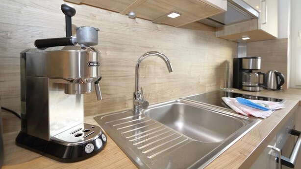 A modern kitchen with a De'Longhi espresso machine, stainless steel sink, and a kettle. - Duck nest at the village pond (Wenningstedt-Braderup (Sylt))