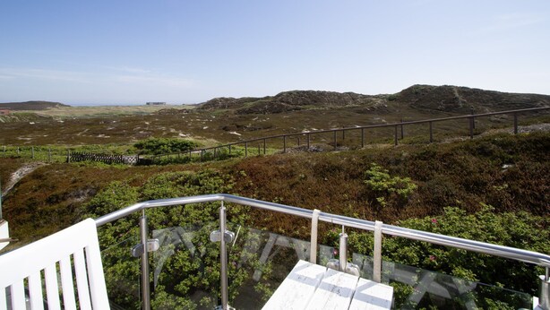 A scenic outdoor area with a metal railing, a white bench, and a pathway leading through a natural landscape. - Apartment Filter, Germany (Hörnum (Sylt))