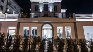 Un edificio grande de dos pisos con balcón y un amplio arco de entrada.