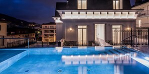 Een seizoensgebonden buitenzwembad en ligstoelen