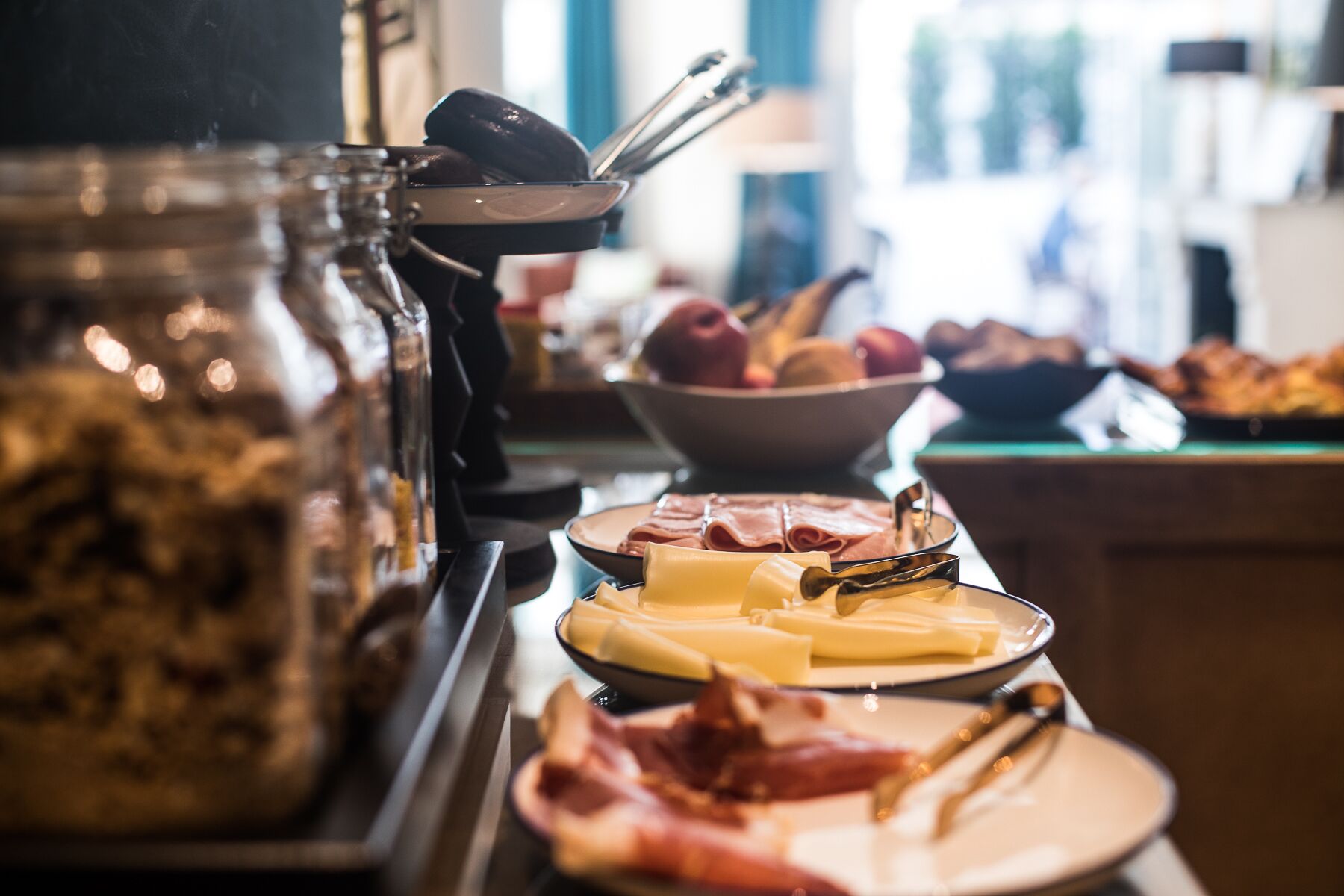 Un bufé con diversas opciones de comida, incluyendo carnes, quesos y frutas.