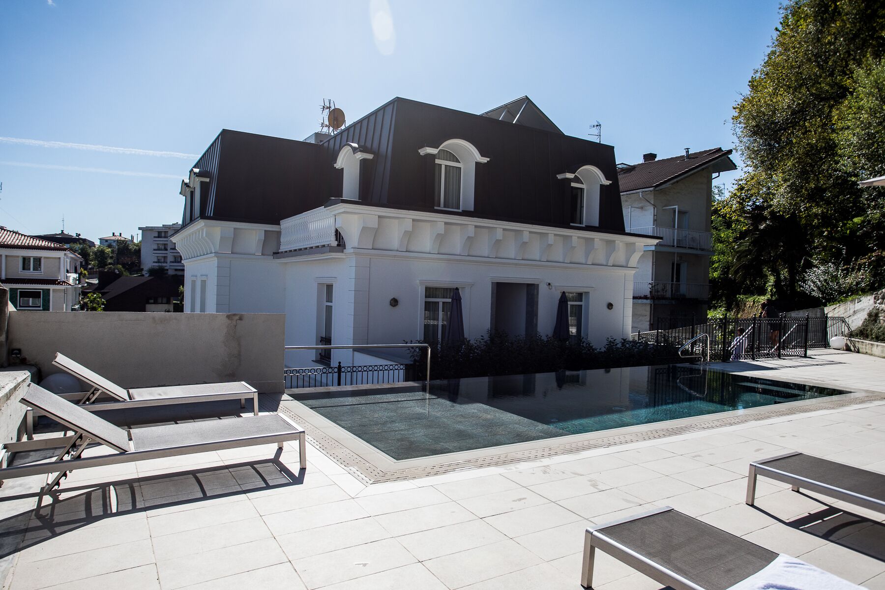 Un edificio de dos pisos con piscina y mobiliario exterior.