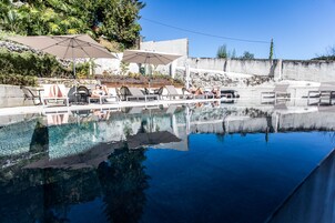 Una piscina al aire libre de temporada, sombrillas