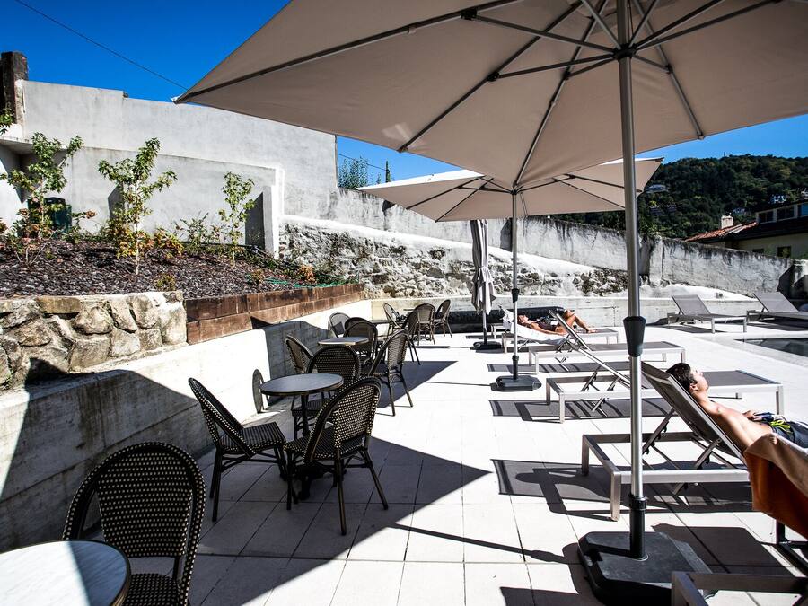 Un patio al aire libre con mesas, sillas, sombrillas y sillones.