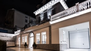 Un hotel con fachada blanca, un balcón con barandillas negras y una gran entrada en arco.