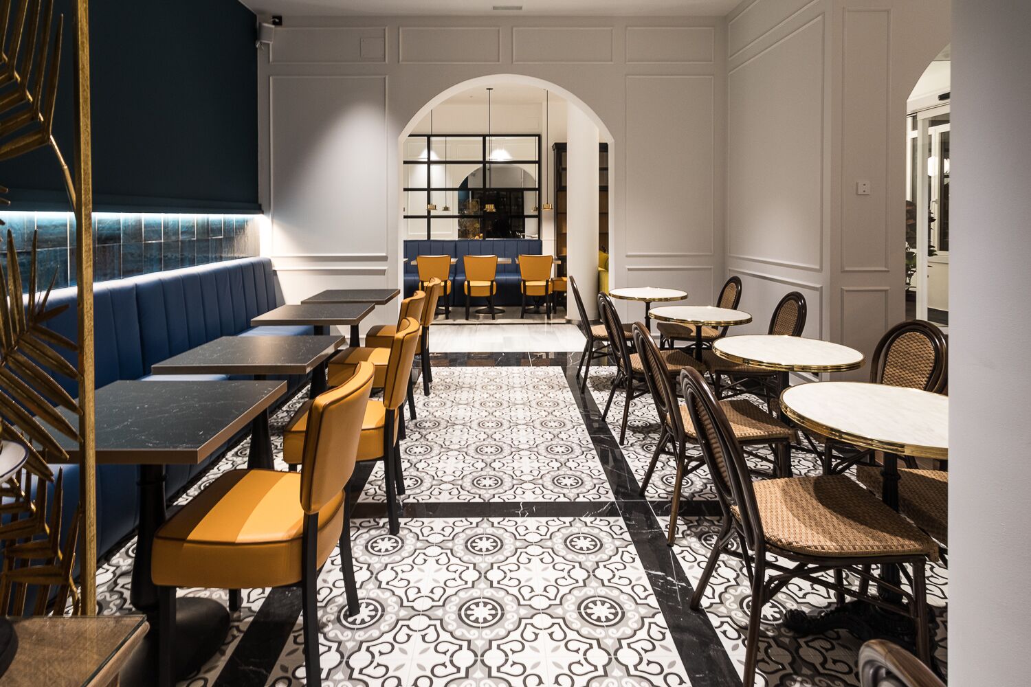 Un restaurante con una mezcla de cabinas y mesas, un suelo con estampado y vistas al área de la cocina.
